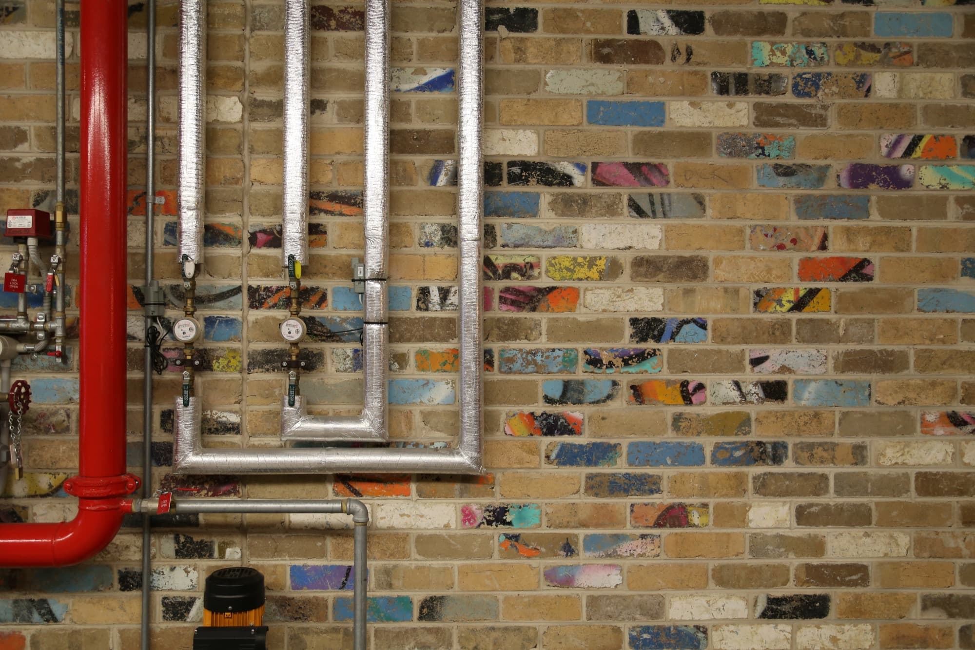 The entry is assembled from salvaged bricks, which still bear the colors of old graffiti.