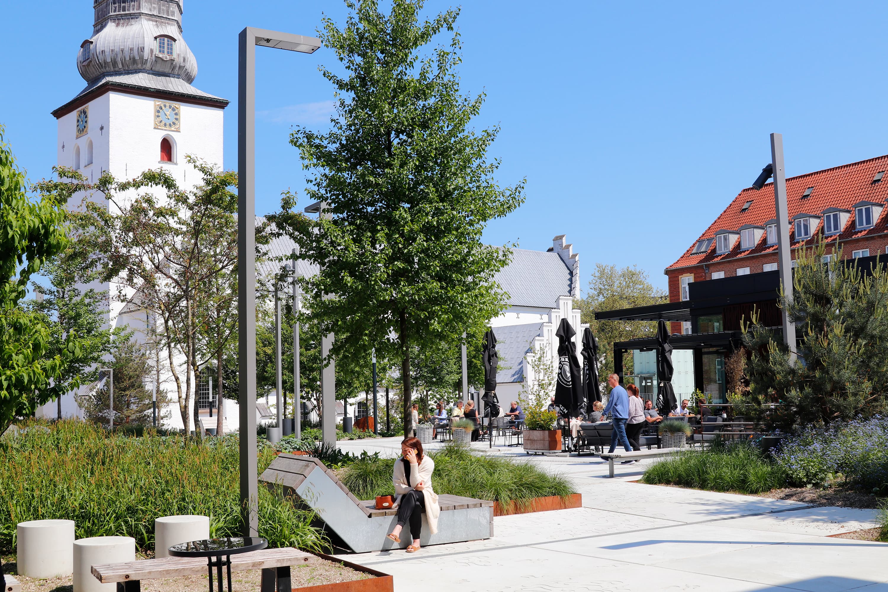 Budolfi Plads - grøn beplantning og kirke i baggrunden
