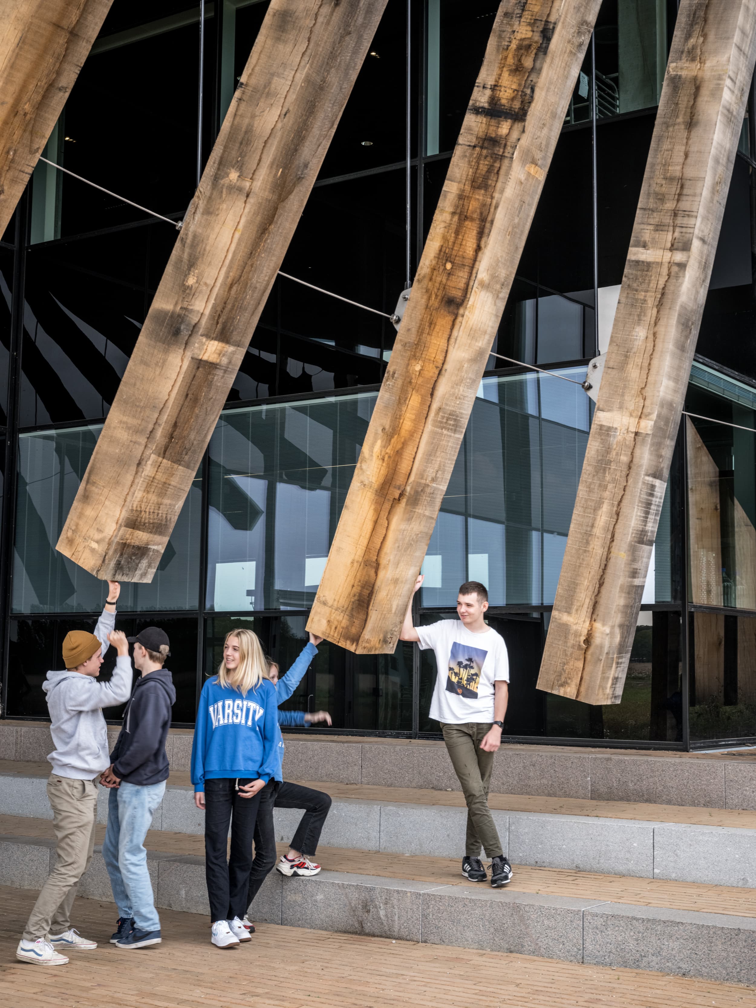 LIFE Campus - 3 skoleelever der står ved egetræssøjler ved facaden